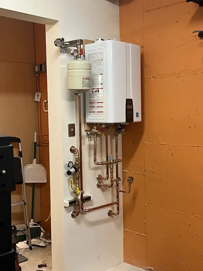 Plumbing technician inspecting water heater connections in Caln
